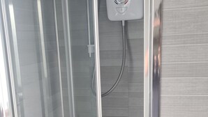 A glass-enclosed shower stall with a control panel, a handheld showerhead, and a handheld massager. - Ravenhill Town house  Belfast (Belfast)
