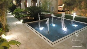 A modern indoor pool with multiple water features, surrounded by lush greenery and a stone pathway. - hihome – Mandai Flat (Cabo Frio)