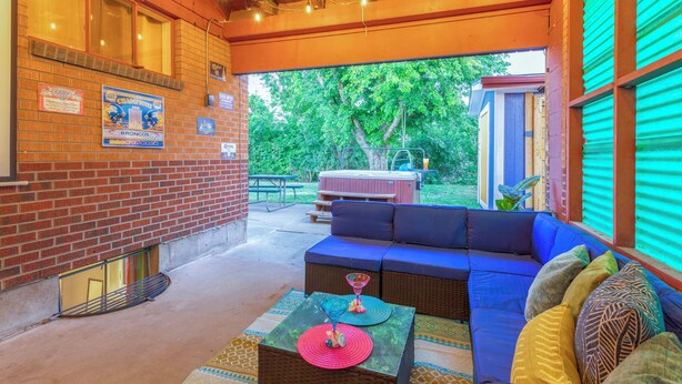 A covered patio with a brick wall, a blue sofa, and a table with decorative items.