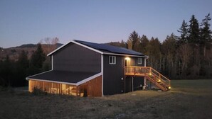 Une grande grange aux couleurs sombres, avec un escalier en bois menant à un deuxième étage.
