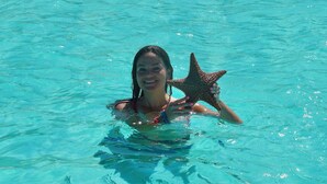 A person in a pool holding a starfish. - Aqua Village Resort (Stocking Island)