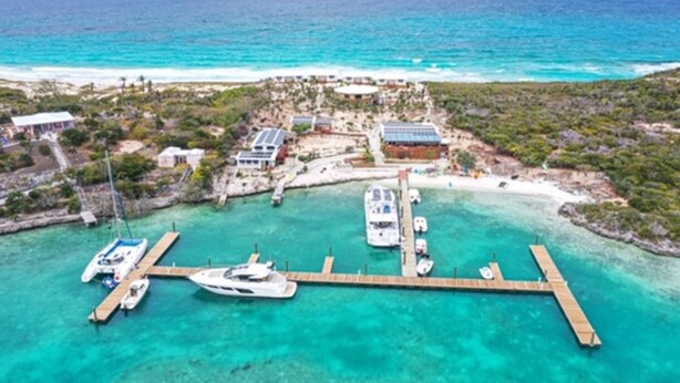 An aerial view of a coastal resort with a marina, clear turquoise waters, and a sandy beach. - Aqua Village Resort (Stocking Island)