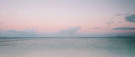 A kayak on a sandy beach with a calm sea and a clear sky.