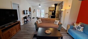 A living room with a TV, a sofa, a coffee table, and a blue couch. - Escape to Tranquility at Whispering Woods Cottage (Haliburton)
