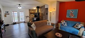 A living room with a stone wall, a fireplace, a blue sofa, and a brown couch. - Escape to Tranquility at Whispering Woods Cottage (Haliburton)