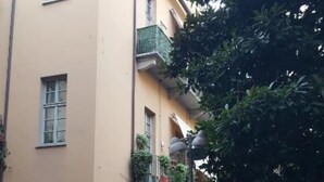 A building with a cobblestone courtyard, a bike parked outside, and a metal fence.