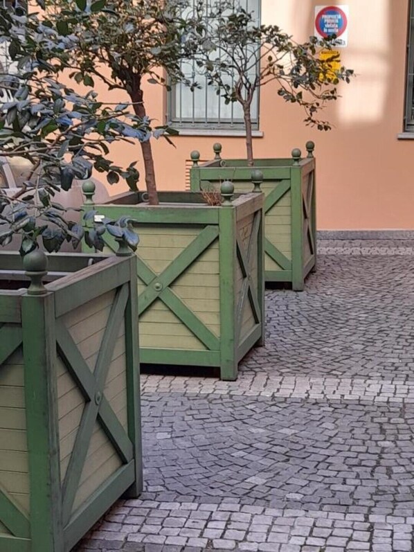 Ein Innenhof mit grünen Pflanzgefäßen und einem Kopfsteinpflasterboden.