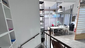 A staircase leading to a dining area with a high ceiling, pendant lighting, and a view of the kitchen area.