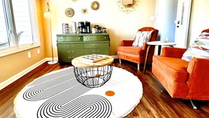 A living room with a green dresser, a round coffee table, and two orange armchairs. - Iconic Dahlonega View! In Town! WINE GOLD HIKING (Dahlonega)
