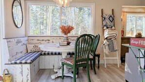 Ein gemütliches Blockhaus-Interieur mit einer Holzbank, einem runden Tisch mit einer Vase und einem Sessel mit Decke.