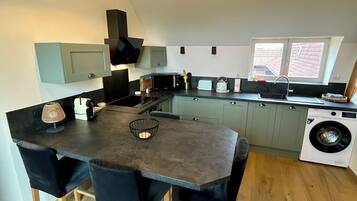 A modern kitchen with a central island, built-in appliances, and a washing machine.