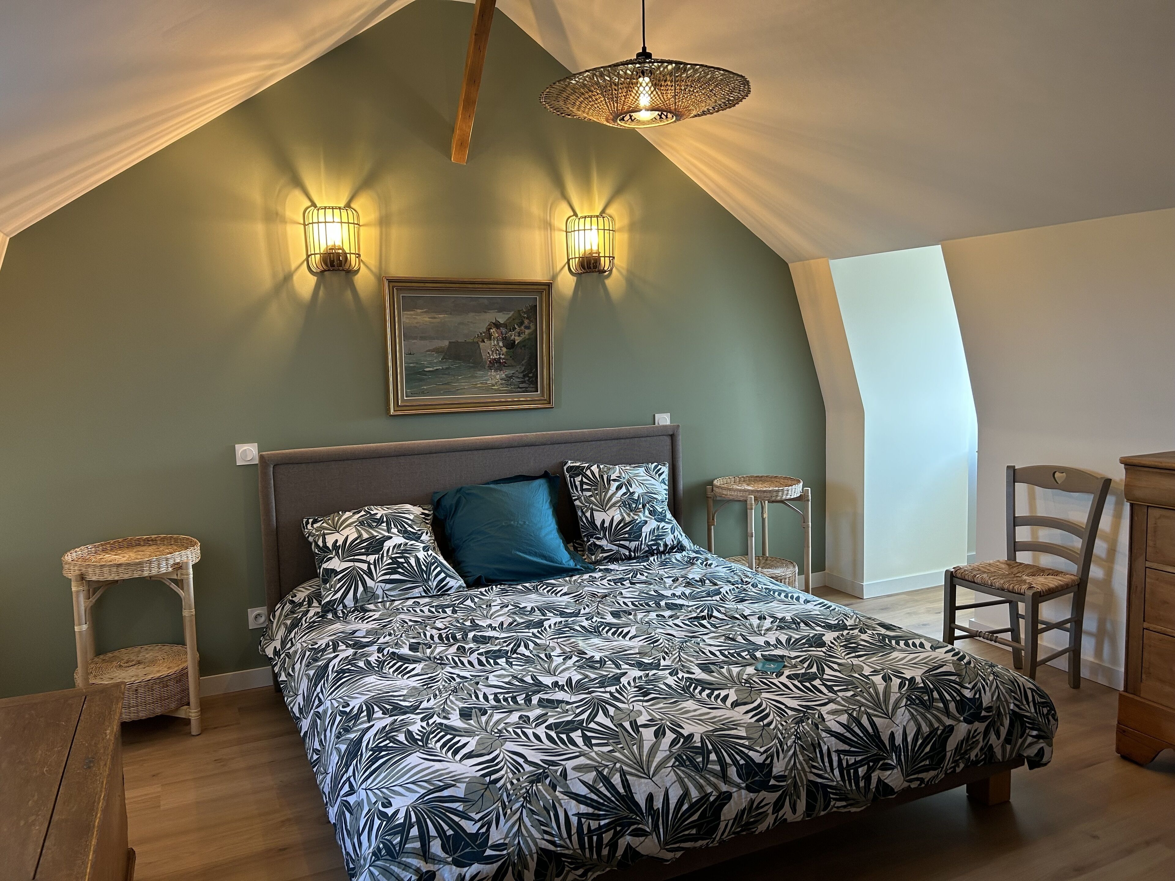 A bedroom with a bed, two wall-mounted lights, a painting, and a wooden ceiling.