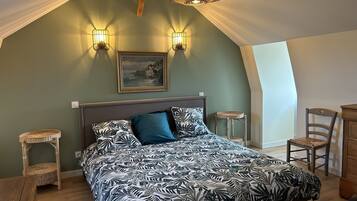A bedroom with a bed, two wall-mounted lights, a painting, and a wooden ceiling.
