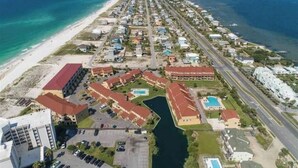 An aerial view of a coastal resort with multiple buildings, a marina, and a beach. - Pensacola Beach - 4 Bedrooms w/ Beach and Pool Access! (Pensacola Beach)