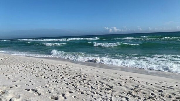 A beach with footprints in the sand and waves crashing onto the shore. - Pensacola Beach - 4 Bedrooms w/ Beach and Pool Access! (Pensacola Beach)