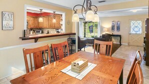 A wooden dining table with chairs, a kitchen area with wooden cabinets, and a chandelier. - Timber View Retreat-Large 4 BR close to shopping & restaurants in NE Longview (Longview)