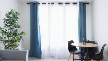 Une pièce moderne avec une table ronde, des chaises noires, un canapé gris et une plante en bambou.