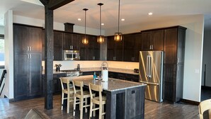 Una cocina moderna con armarios de madera oscura, electrodomésticos de acero inoxidable y una isla central con asientos.