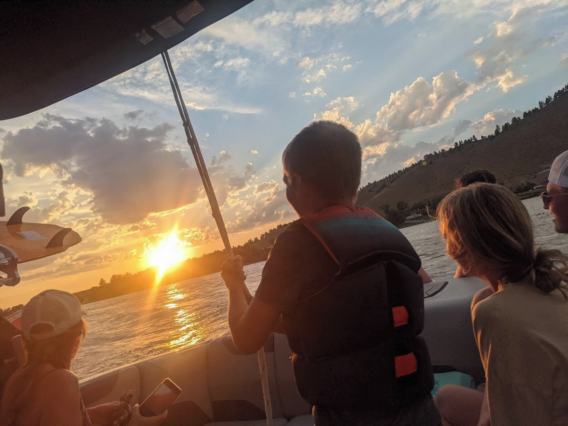 Um barco com passageiros apreciando a vista do pôr do sol.
