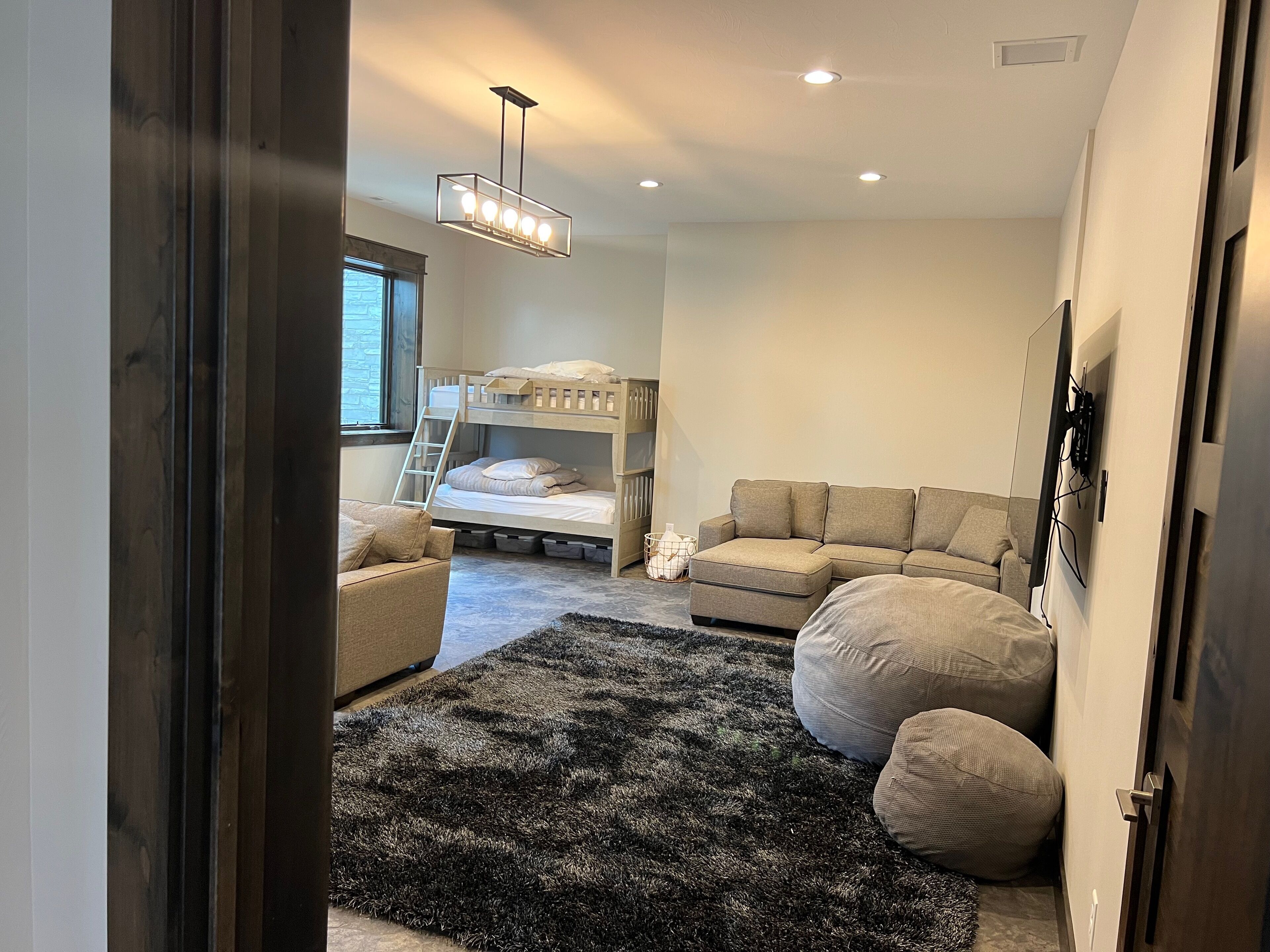 A bedroom with bunk beds, a sofa, a rug, and a ceiling light fixture.