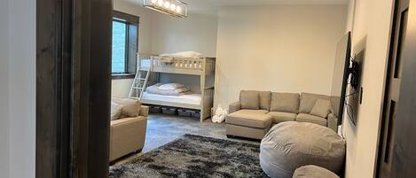 A bedroom with bunk beds, a sofa, a rug, and a ceiling light fixture.