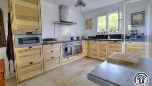 Une cuisine moderne avec des meubles en bois, des appareils en acier inoxydable et une grande fenêtre qui laisse entrer la lumière naturelle.