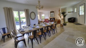 Un espace repas avec une longue table dressée pour le repas, entourée de chaises.