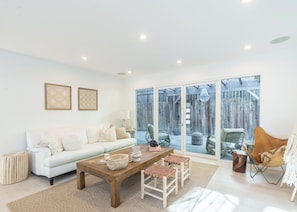 Un salón amplio con un sofá blanco, una mesa de centro de madera y sillones de mimbre.