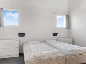 A twin room with two single beds, a dresser, two nightstands, and a window with curtains.
