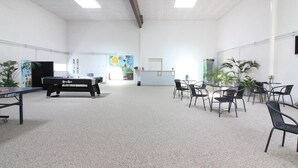 Une pièce spacieuse équipée d’une table de billard, de plusieurs chaises et de plantes en pot.