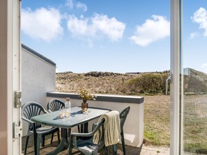 Un patio al aire libre con una mesa y sillas, una botella y un florero con flores.