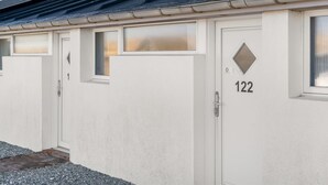 Une rangée de portes blanches portant les numéros 1, 122 et 123, ce qui indique qu’il s’agit d’un hôtel ou d’un immeuble d’appartements.
