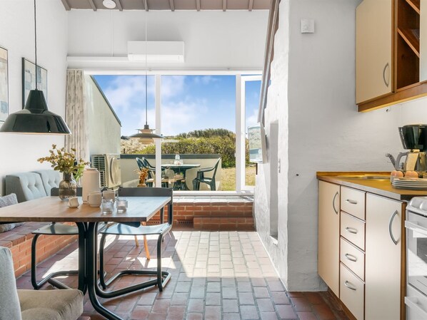 A modern kitchen with a dining area, large windows, and a view of the outdoors.