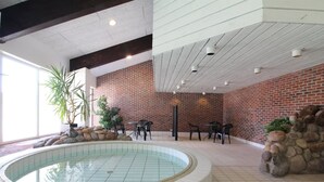 Une piscine intérieure dotée d’un sol carrelé, entourée de murs en briques et agrémentée d’éléments en pierre.