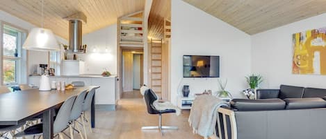 A modern interior with a dining area, kitchen, living room, and a staircase leading to an upper level.