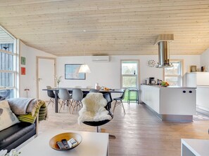 A modern kitchen with white cabinets, a stainless steel range hood, and a dining area with a table and chairs. - "Elni" - 900m from the sea by Interhome (Hals)