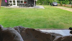 A bedroom with a view of a backyard that includes a patio, outdoor furniture, and a car parked outside.