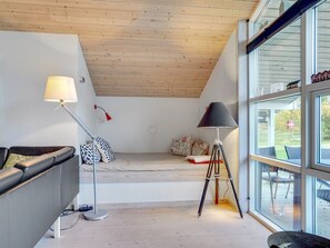 A modern room with a loft bed, a sofa, a floor lamp, and a tripod lamp. - "Elni" - 900m from the sea by Interhome (Hals)