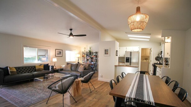 Una sala de estar moderna con un sofá, sillas, una mesa de comedor y una cocina al fondo.