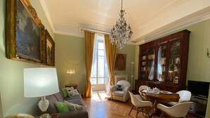 Una sala de estar con sofá, sillones, una mesa de comedor y una araña.