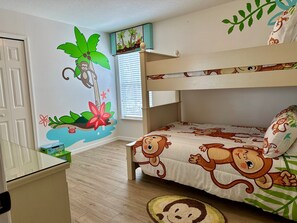 A child's bedroom with a bunk bed, a wall mural, and a window with blinds.