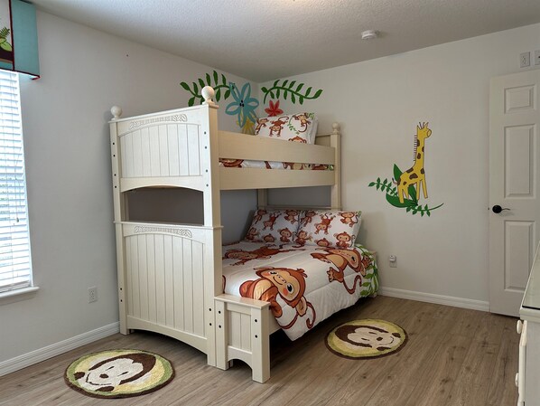 A bunk bed with a monkey-themed bedspread, a giraffe wall decal, and a circular rug with a monkey design. - Fantastic 6 Bed/4.5 Bath w/Hot Tub/Pool by Disney! (Kissimmee)