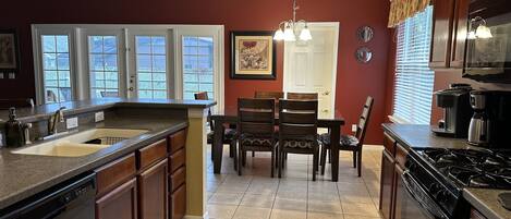 A kitchen with a granite countertop, a dishwasher, a stove, and a dining area with a table and chairs.