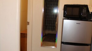 Une cuisine compacte équipée d’un réfrigérateur Galanz et d’un four à micro-ondes placé sur le dessus.