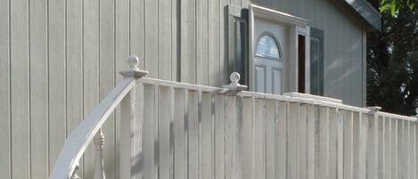 A wooden deck with a white railing and a door leading to a building.