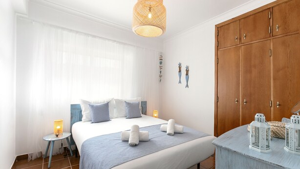 Ein Schlafzimmer mit Bett, Nachttischen, einem Kleiderschrank und dekorativer Wandgestaltung.