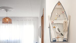 Ein Wohnzimmer mit einem blauen Sofa, einer Pendelleuchte und Wanddekoration im maritimen Stil.