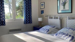A bedroom with a large bed, a nightstand, a framed picture, and a window with curtains. - La Rouvraie - FLAYOSC (FLAYOSC)