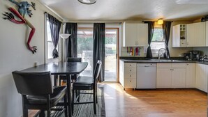 Uma cozinha compacta com área de refeições, piso de madeira e vista pela porta de vidro.