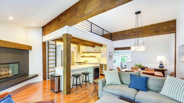 A spacious living area with a wooden ceiling, a fireplace, a kitchen with stools, and a dining area with a table and chairs. - Walk to Main St & Lifts: Ketchum Townhouse! (Ketchum)